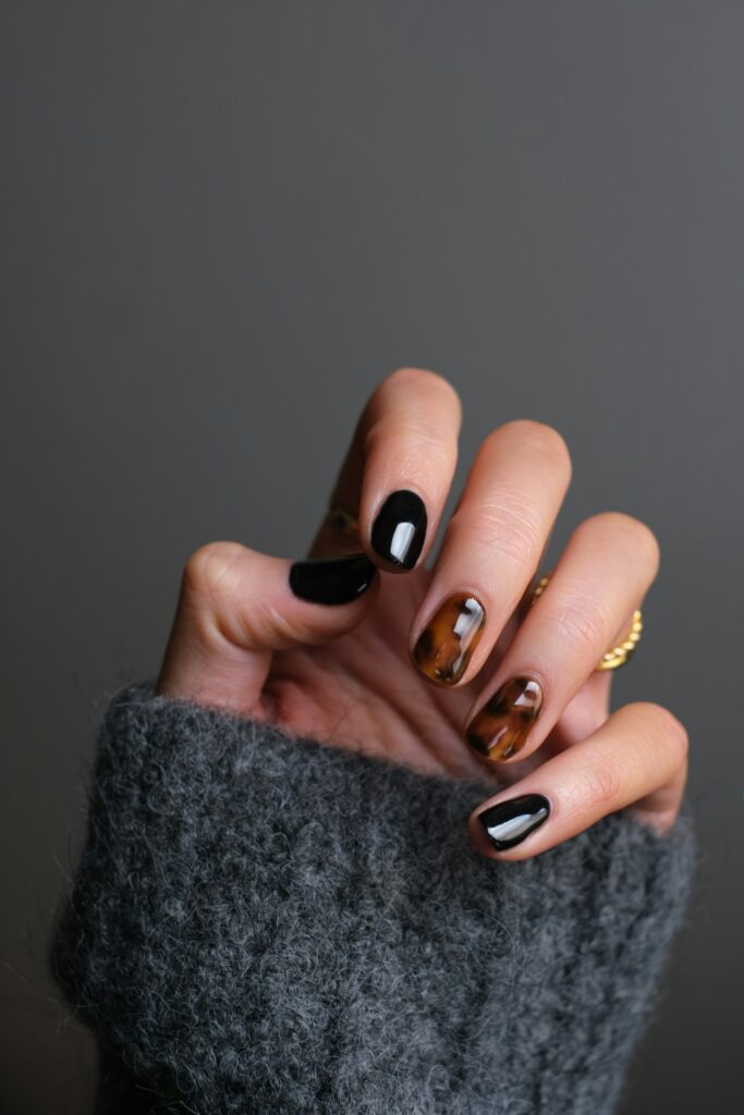 Nail art met zwarte en schildpad-nagels en een gouden ring
