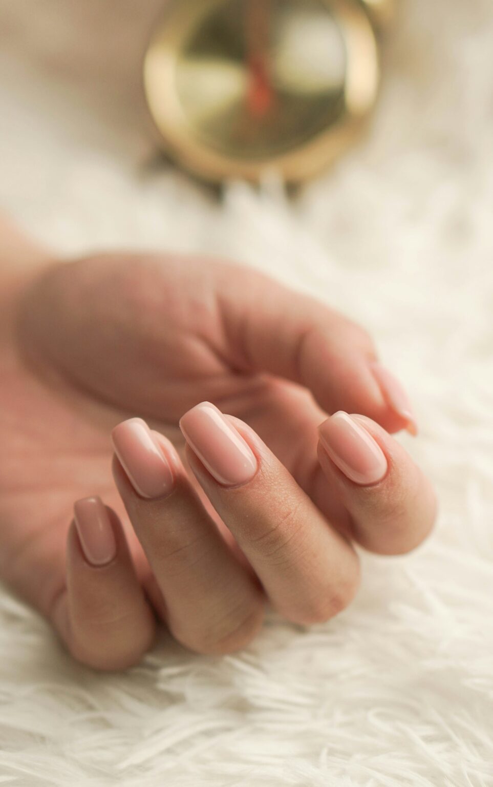 Hand met zachtroze manicure op wit linnen